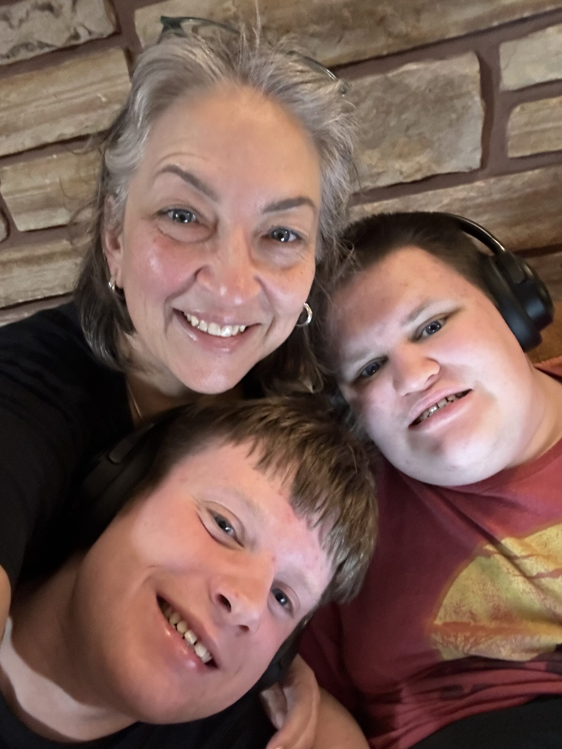 Stacey with her twin boys O and W, smiling and embracing, representing family caregiver support at Willowjak Services
